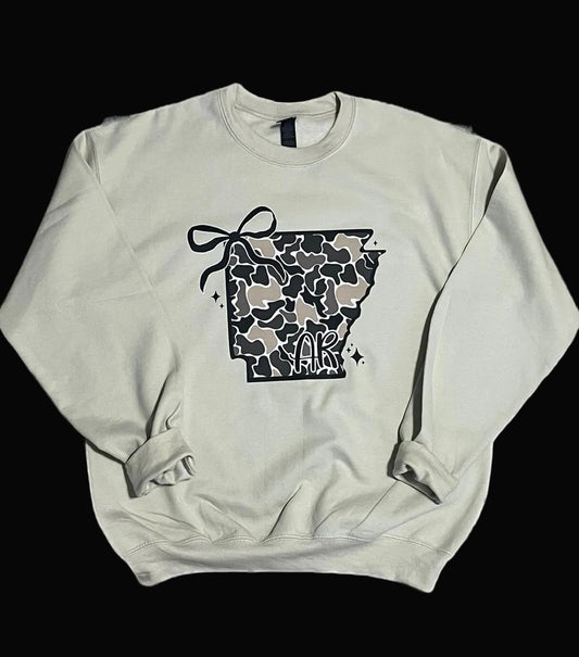 tan sweatshirt with arkansas state in camo and a bow on top side on white black background