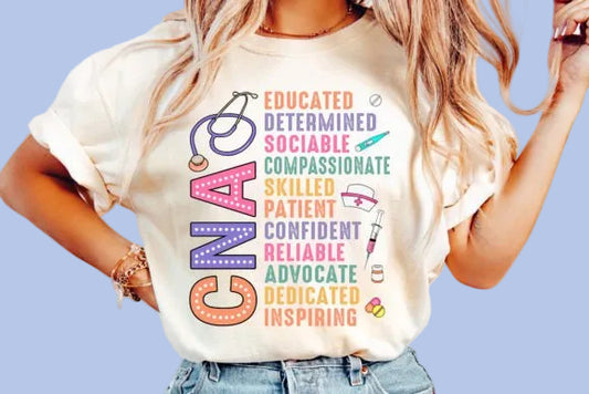 A person wearing a beige t-shirt with text printed on it that describes positive traits such as educated, determined, social, compassionate, patient, and adventurous, related to the field of CNA.