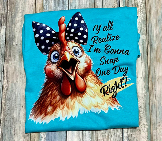 A blue t-shirt with a graphic print of a chicken wearing polka-dot hairbow and the text 'Y'all realize think I'm gonna snap one day right?'.