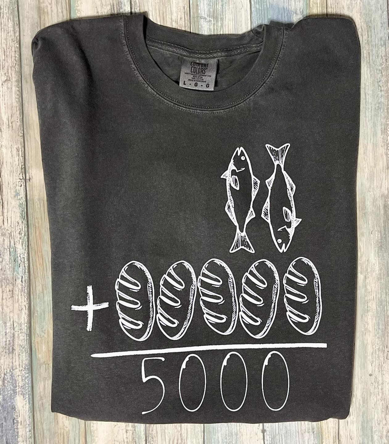 Pepper color long sleeve crew neck t-shirt with white drawings of two fish and five loaves, and the text 'JESUS FED 5000' below them.