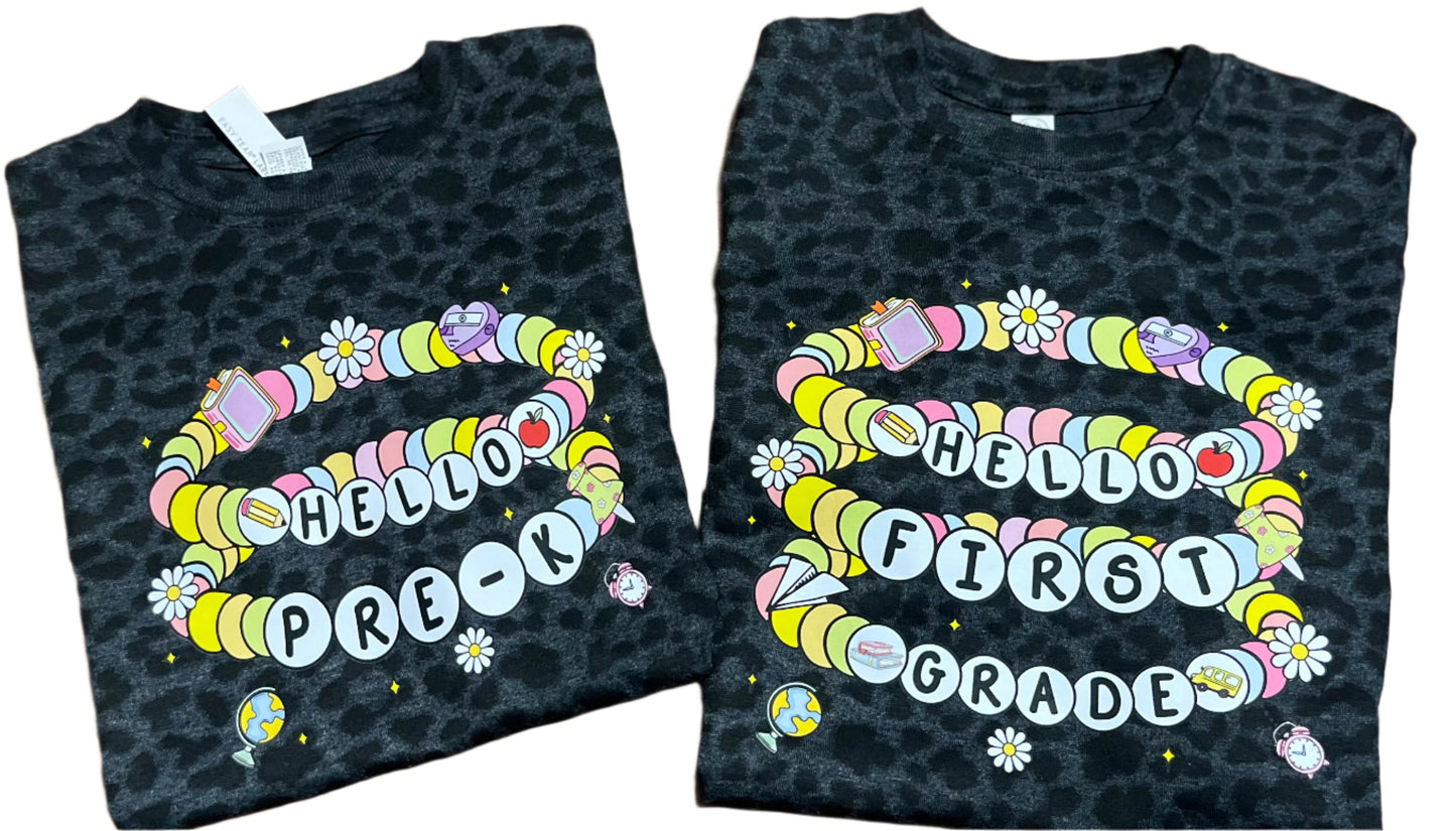 two black leopard tshirt with friendship bracelets saying hello pre-k and hello first grade on white background