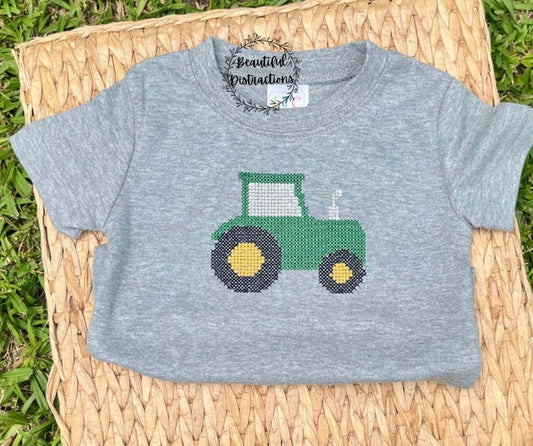 grey child tee with embroidered cross stitch detail green tractor lying on whicker platter and has beautiful distractions decal on it