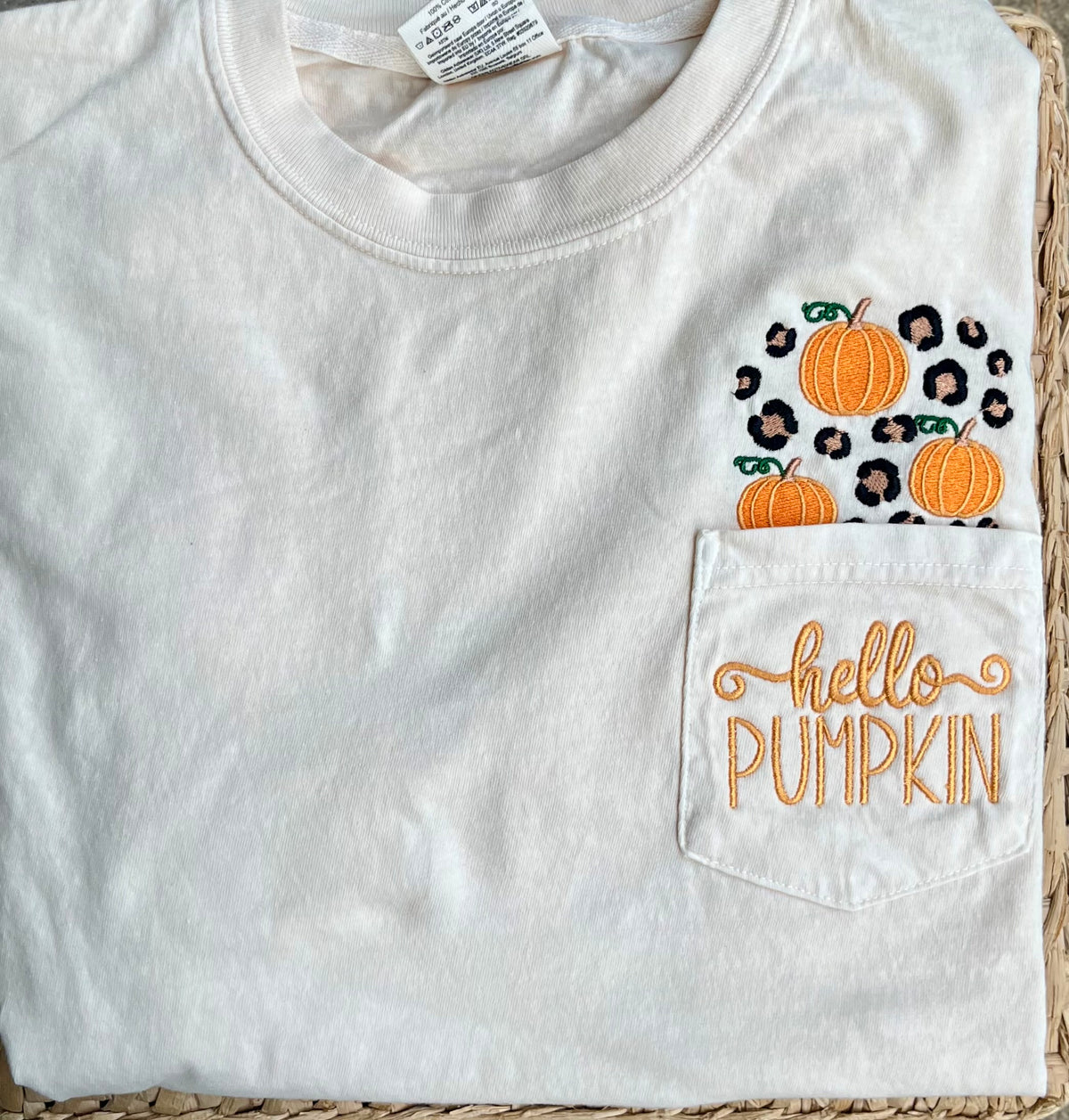 Comfort colors short sleeve pocket tee in the color ivory with 
Embroidered pumpkins and leopard spots above the pocket with hello pumpkin embroidered on the pocket area lying on woven surface

Pocket will be sewn shut

Personalization available - Hello pumpkin will be sewn on the pocket unless monogram is requested.
 If adding monogram list name or initials in personalization box in order of first name, last name, middle name
