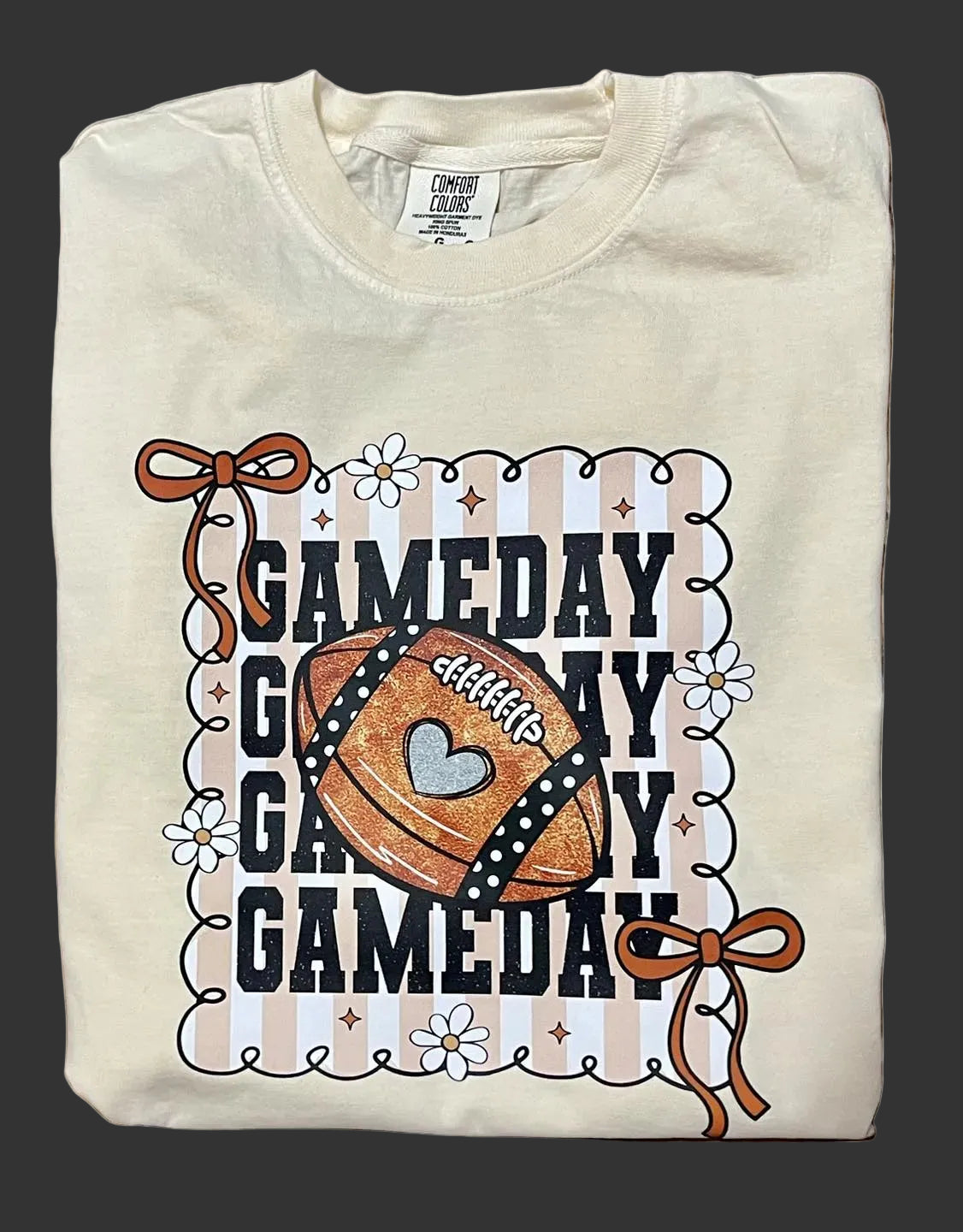 Folded t-shirt with 'GAMEDAY' text and football design on a black surface