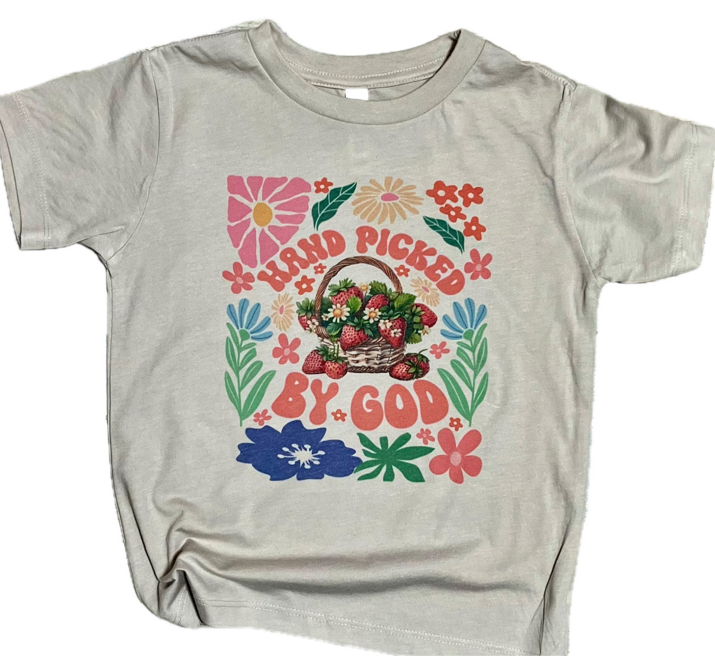 A gray t-shirt with a graphic print of a basket of fruits and flowers and the text 'Handpicked by God'.