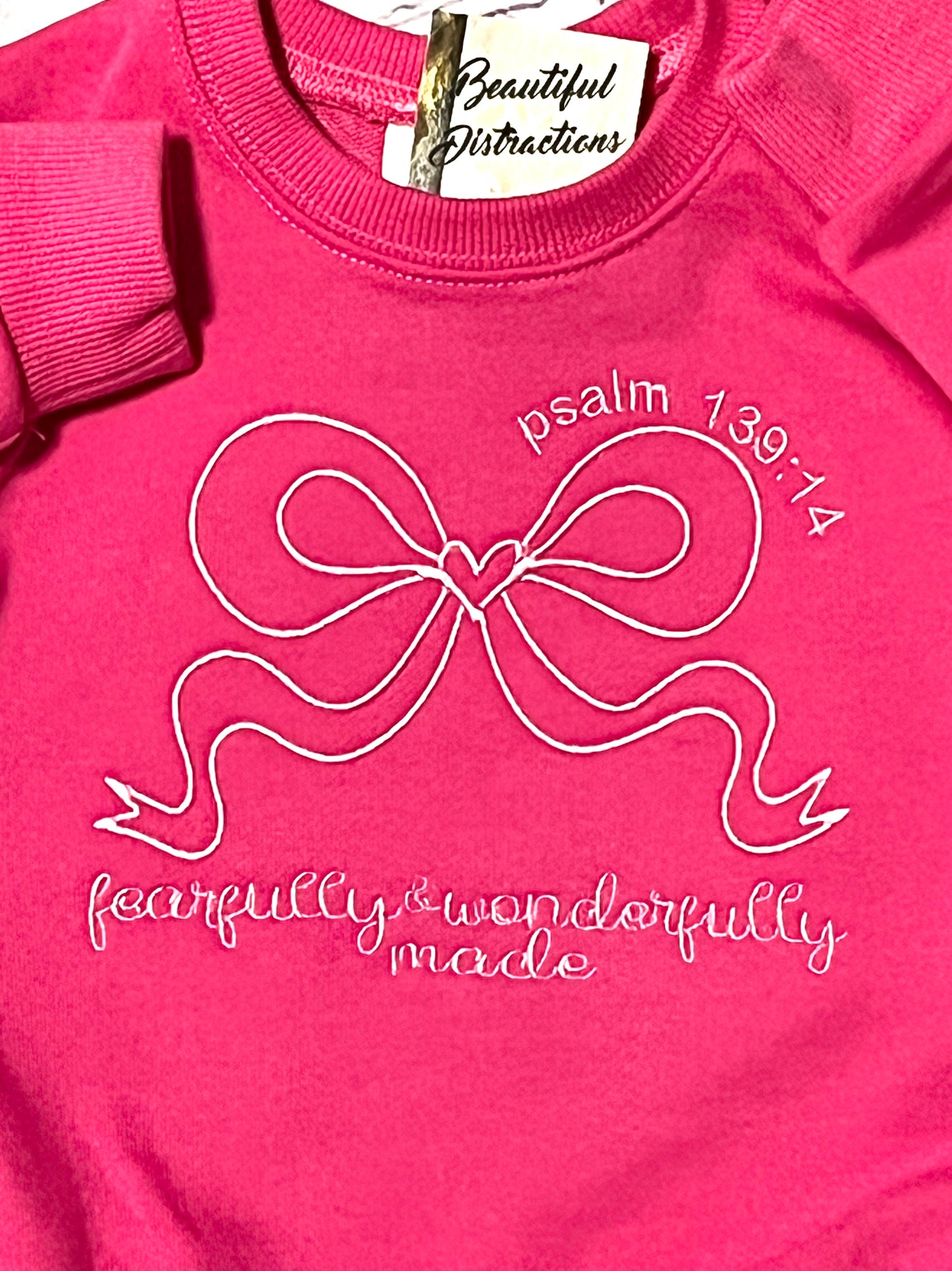 Pink sweatshirt rchild romper with a bow design fearfully and wonderfully made embroidered on a white background
