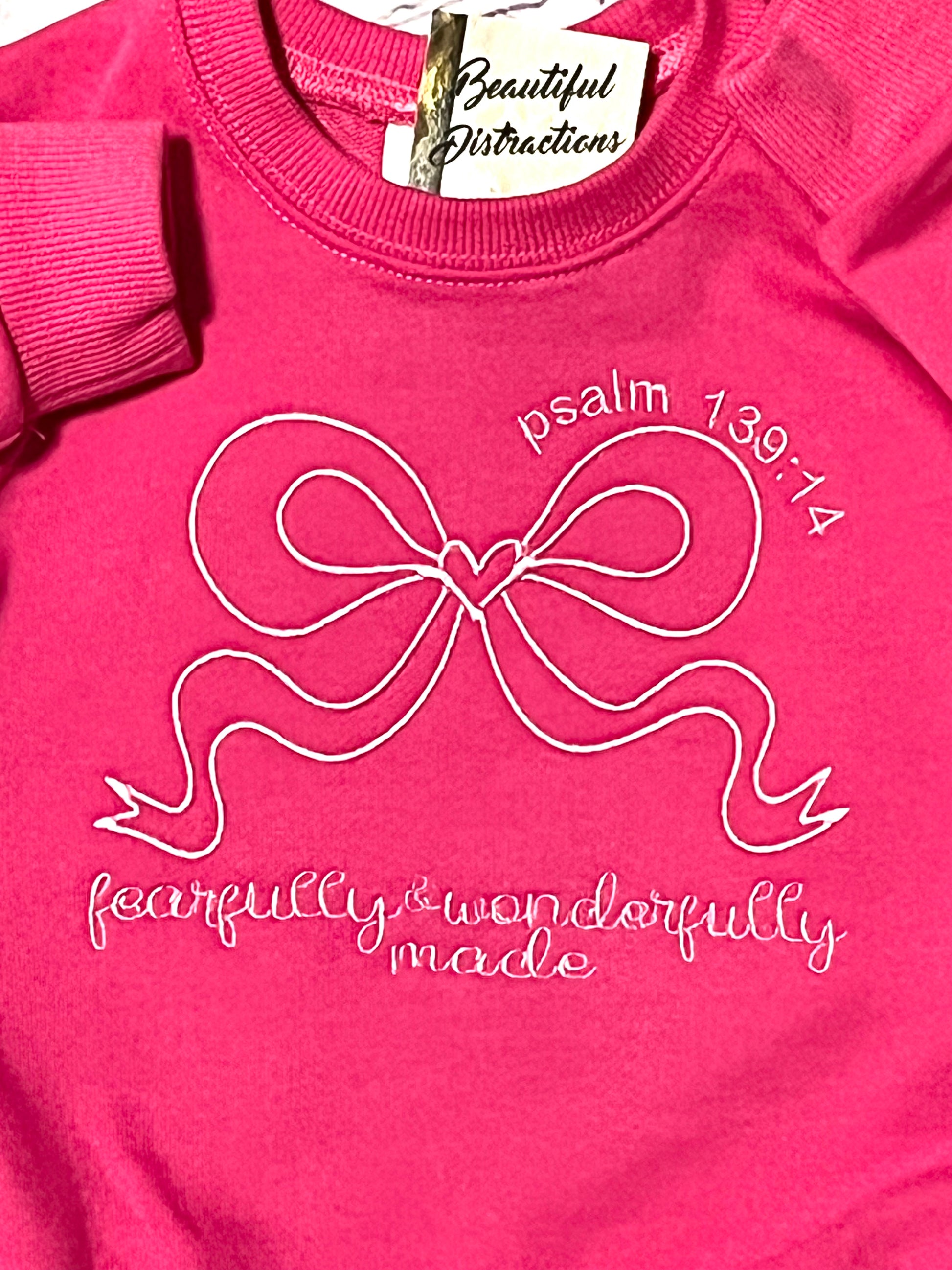 Pink sweatshirt rchild romper with a bow design fearfully and wonderfully made embroidered on a white background