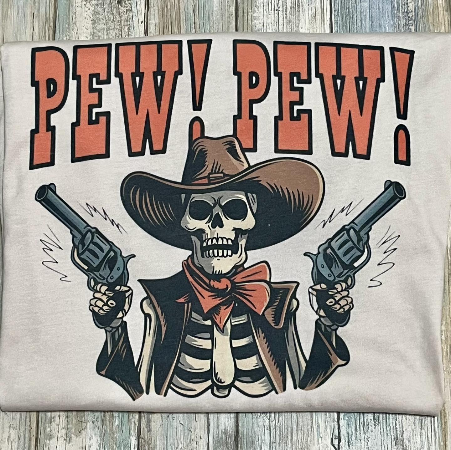 This image features a striking skeleton cowboy tee, showcasing a bold and playful design. The t-shirt is short-sleeved and comes in a natural color, ideal for casual wear.