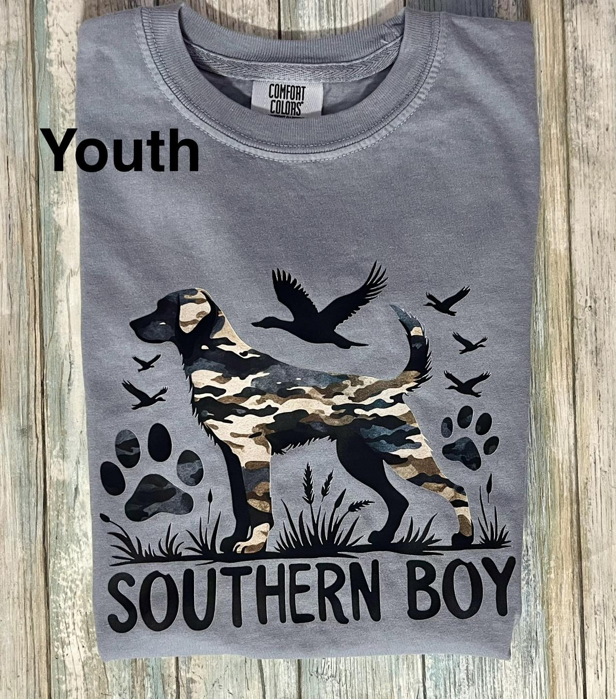 Gray t-shirt with a camouflage dog and bird design, labeled 'Southern Boy', on a wooden surface.