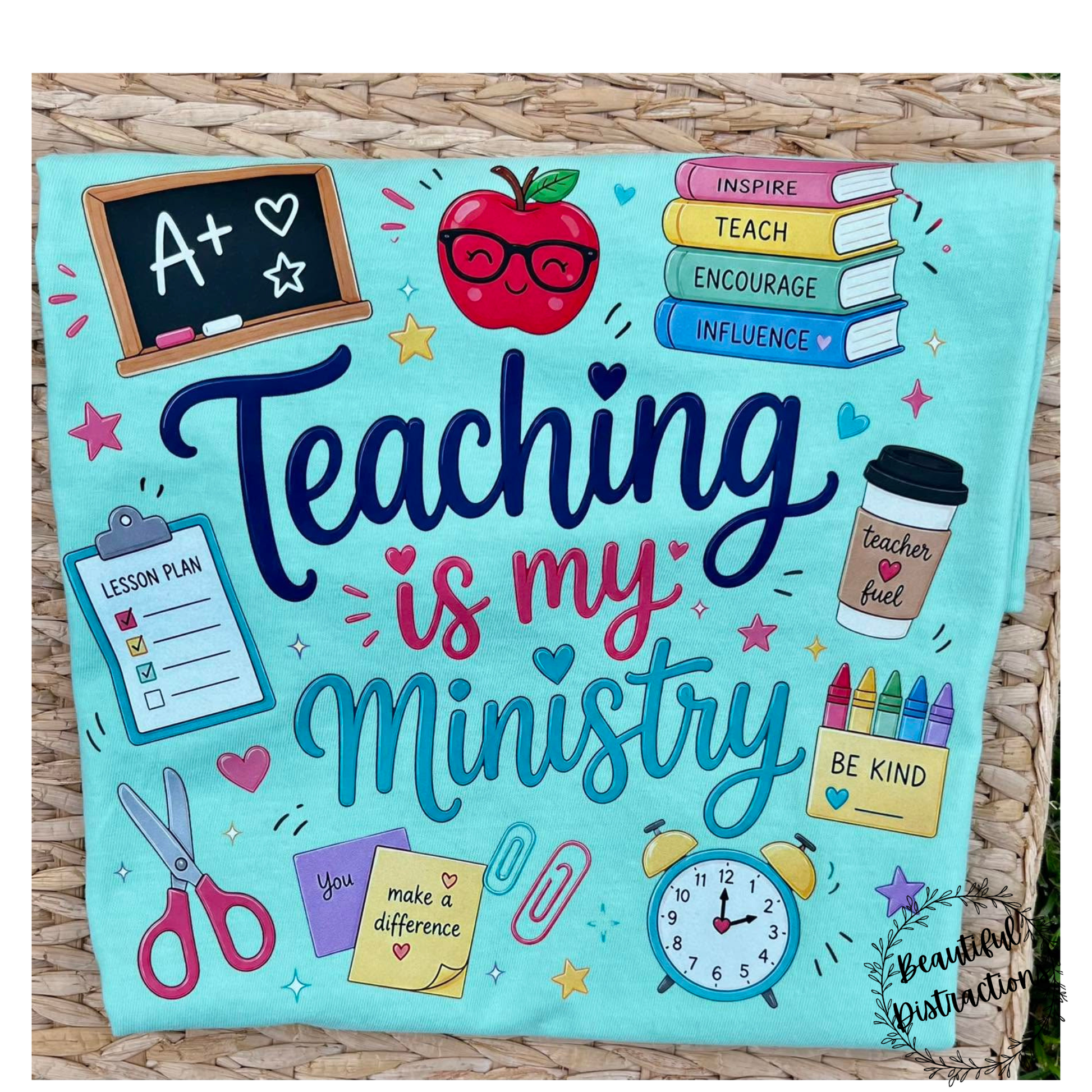 short sleeve tee with printed decal that says teaching is my ministry and has teaching related icons around the words  shirt is in island reef color and is lying on a wicker table