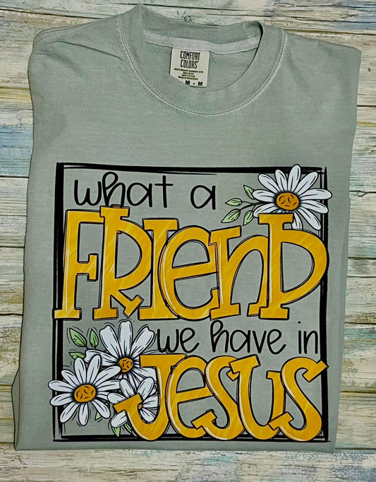 bay color t-shirt with 'What a Friend We Have in Jesus' text and daisy graphics on a wooden surface